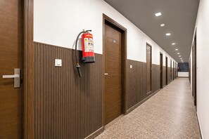 Un pasillo con paneles de madera, un extintor en la pared y puertas con números de habitación.