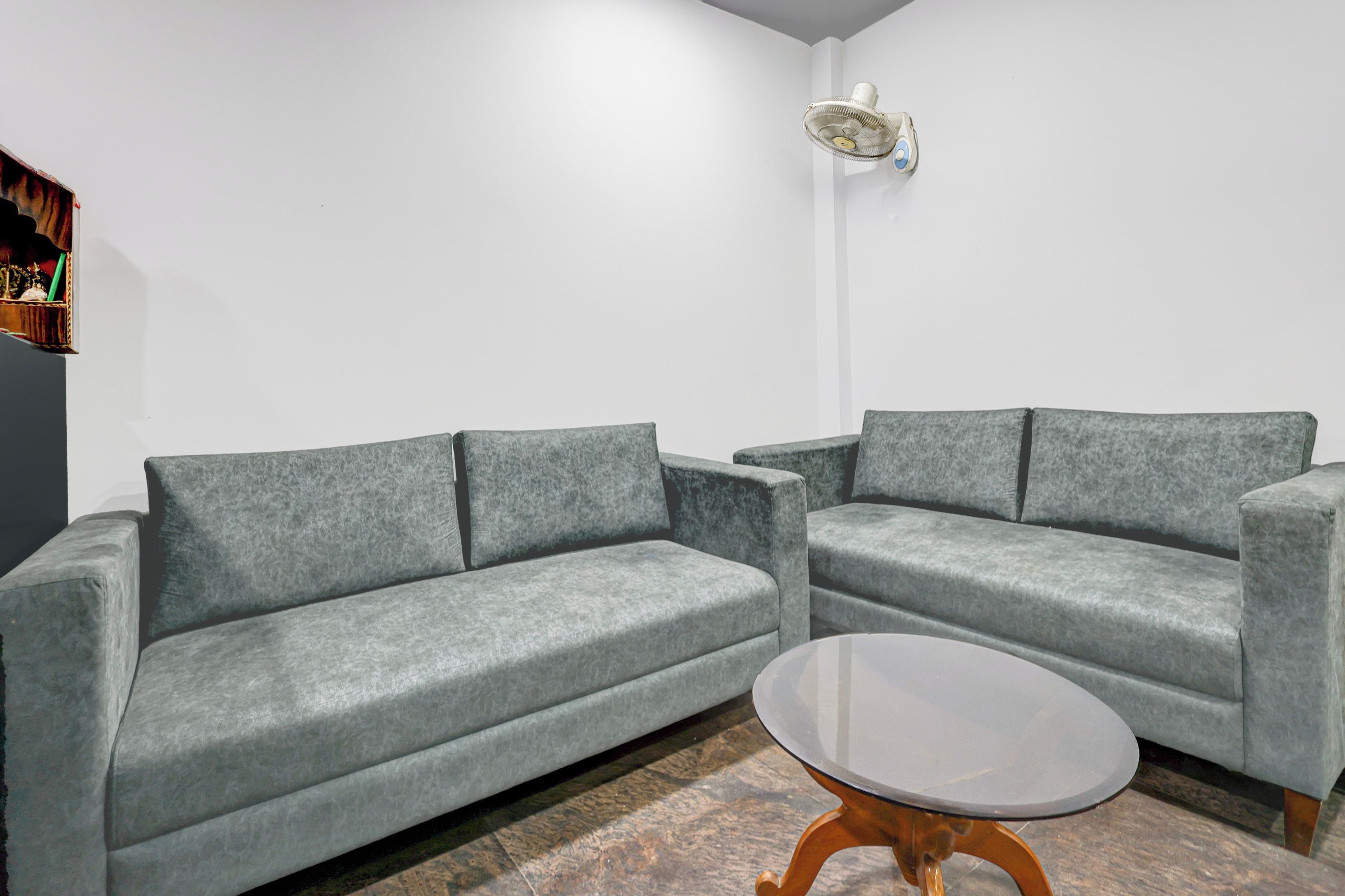 A modern living room with two grey sofas, a small round coffee table, and a wall-mounted light fixture.
