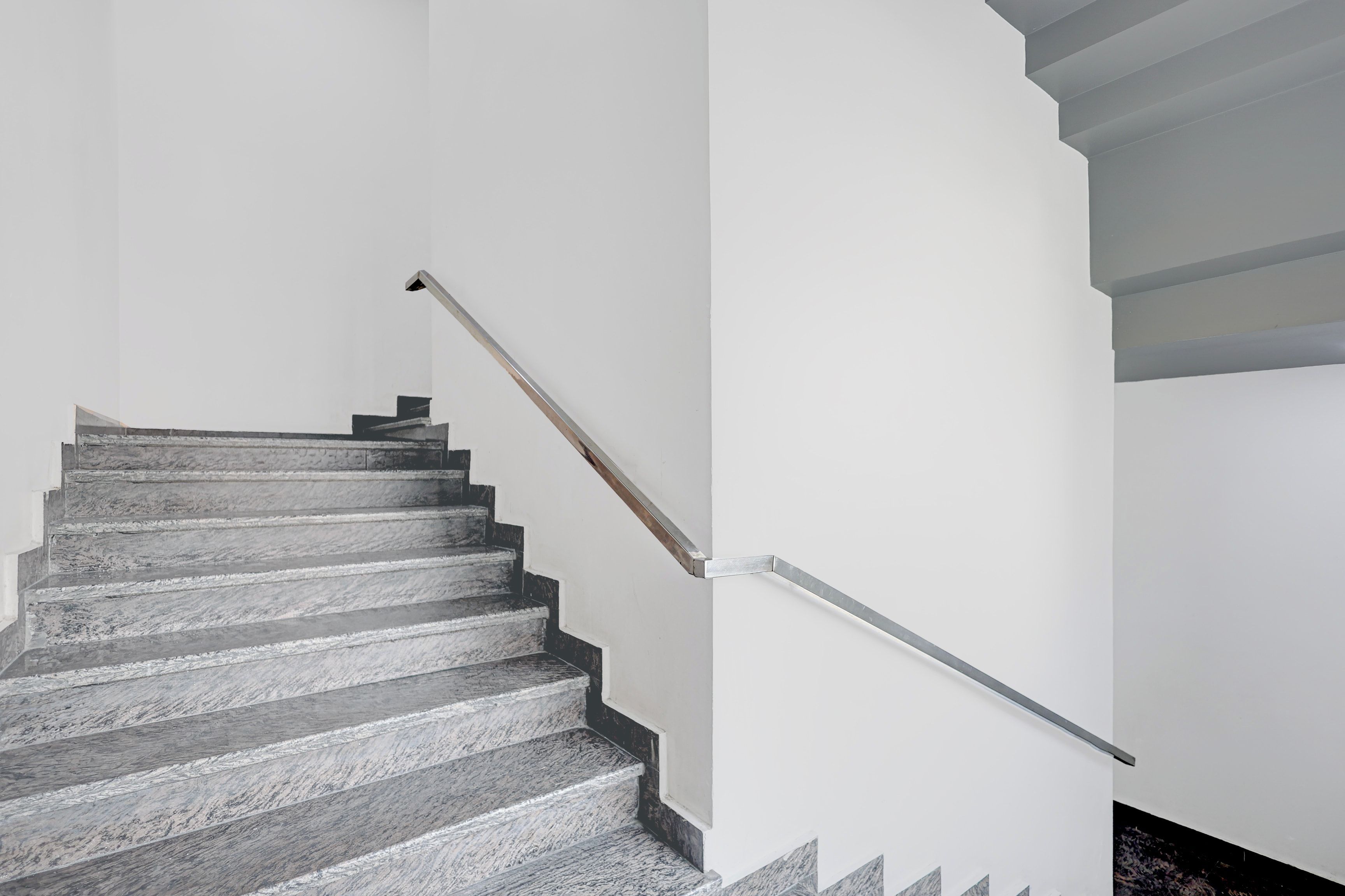 A staircase with a metal handrail and a wooden handrail.