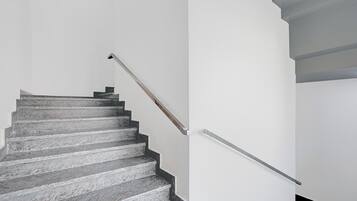 A staircase with a metal handrail and a wooden handrail.
