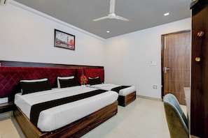 A hotel room with two beds, a red headboard, a ceiling fan, and a framed picture on the wall. - Townhouse Ranipur Mor Formerly Parmila (Haridwar)