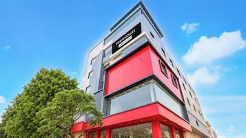 A modern building with a prominent red and grey facade, a visible staircase, and a clear sky.