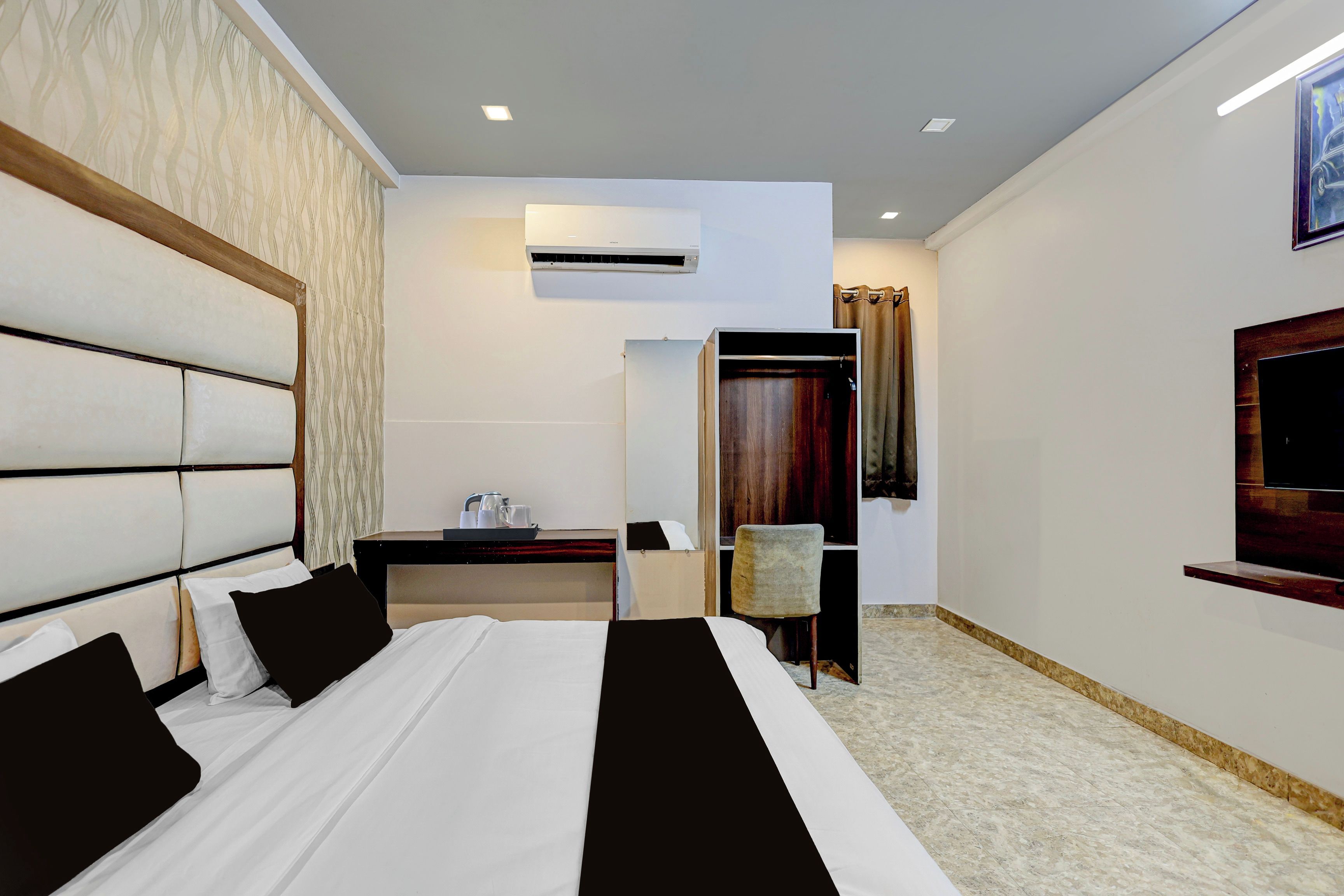 Habitación de hotel con una cama grande, un escritorio, una silla, unidad de aire acondicionado y un televisor en la pared.