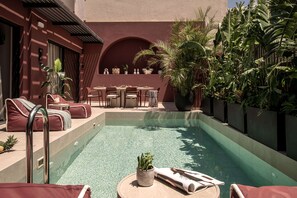 A pool area with lounge chairs, a table, and potted plants. - Moncasa Segreta Collection (Agios Nikolaos)