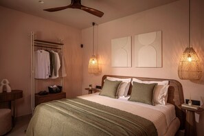 Un dormitorio con cama, armario, ventilador de techo, dos lámparas de pared y una mesita de noche con lámpara.