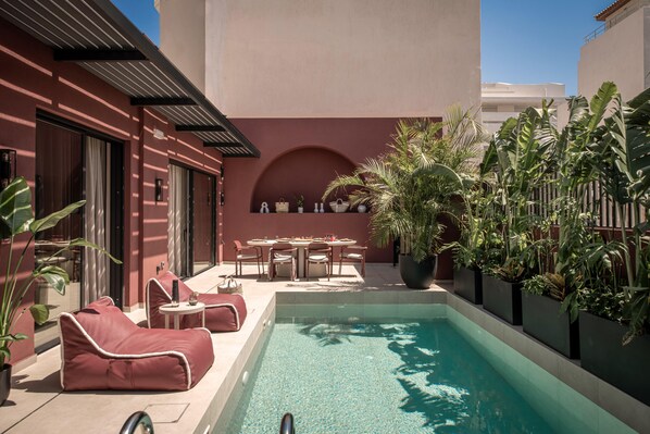 A poolside area with a table and chairs, a small pool, and potted plants. - Moncasa Segreta Collection (Agios Nikolaos)