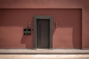 Eine Tür mit einem Schild darüber, ein Briefkasten und eine Wand mit Struktur.