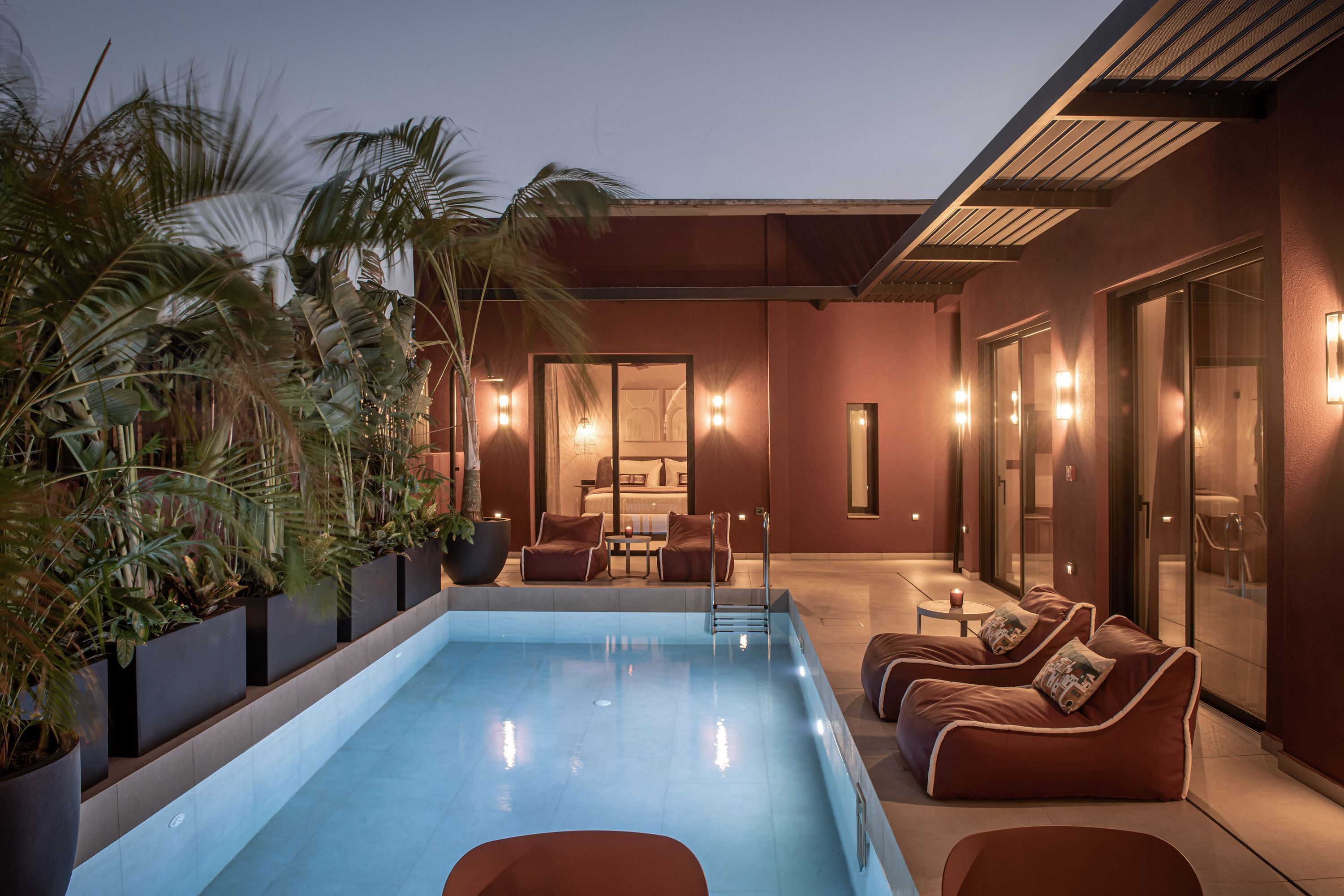 A modern outdoor pool area with lounge seating and a view of the interior.
