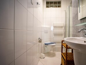 Ein Badezimmer mit Toilette, Waschbecken, Duschkabine aus Glas und Handtuchhalter.