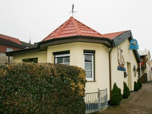 Ein Gebäude mit rotem Ziegeldach, einem Schild und einem kleinen Zaun.
