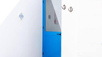 Een blauwe deur met een ruit, een klein decoratief object aan de muur en twee ankers.