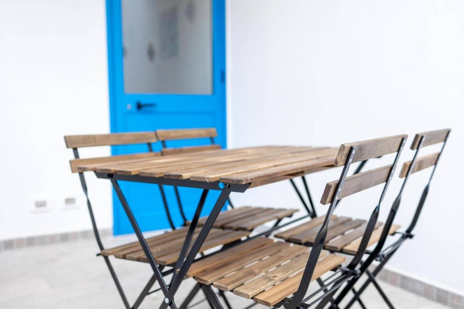 A foldable wooden table and chairs with a blue door in the background.