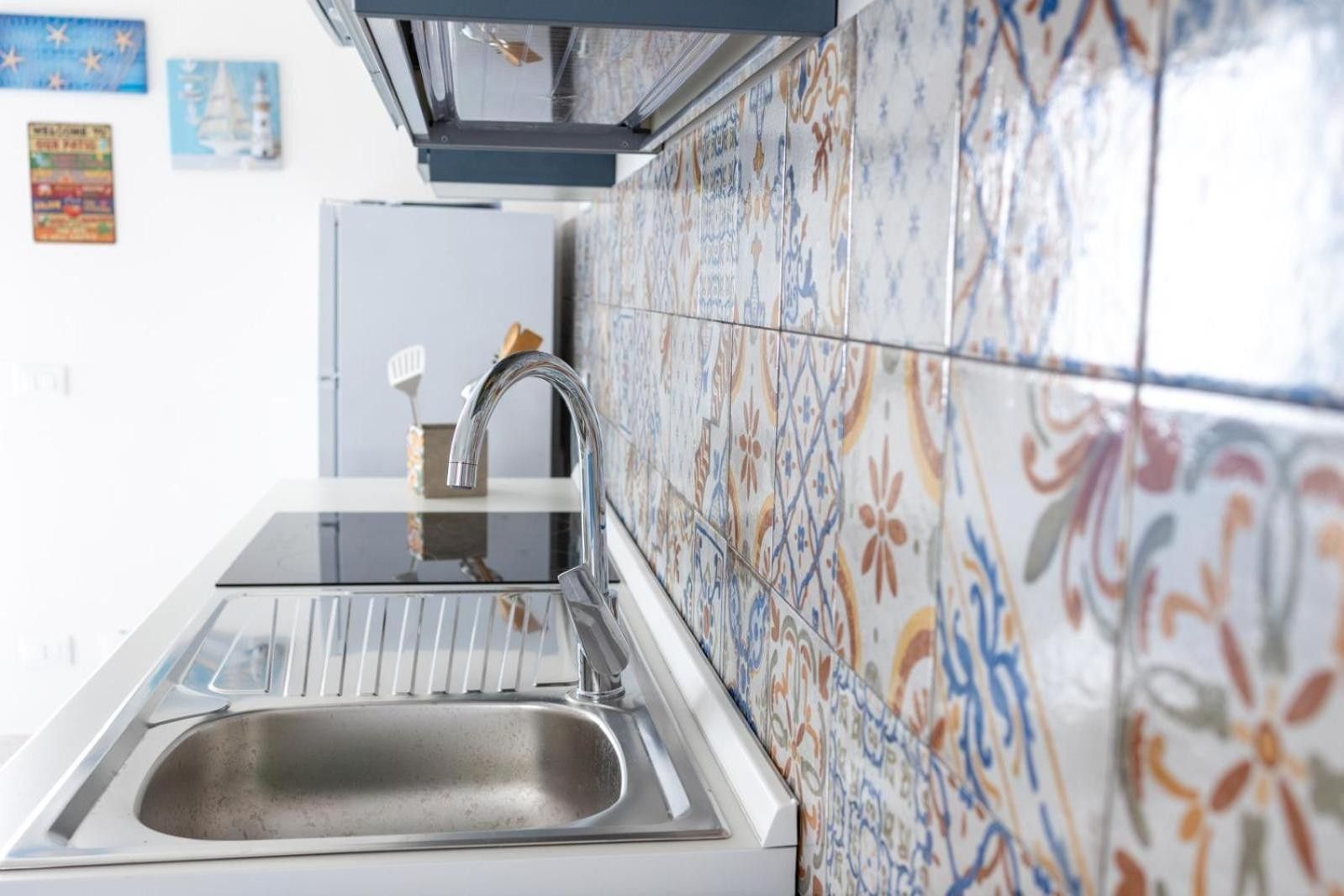 Una cocina con un lavamanos de acero inoxidable, un grifo moderno y azulejos decorativos en la pared.