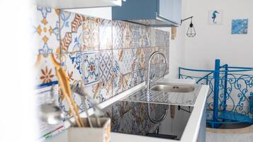 Une cuisine dotée d’un robinet moderne, d’un crédence à motifs et d’une rambarde métallique bleue.