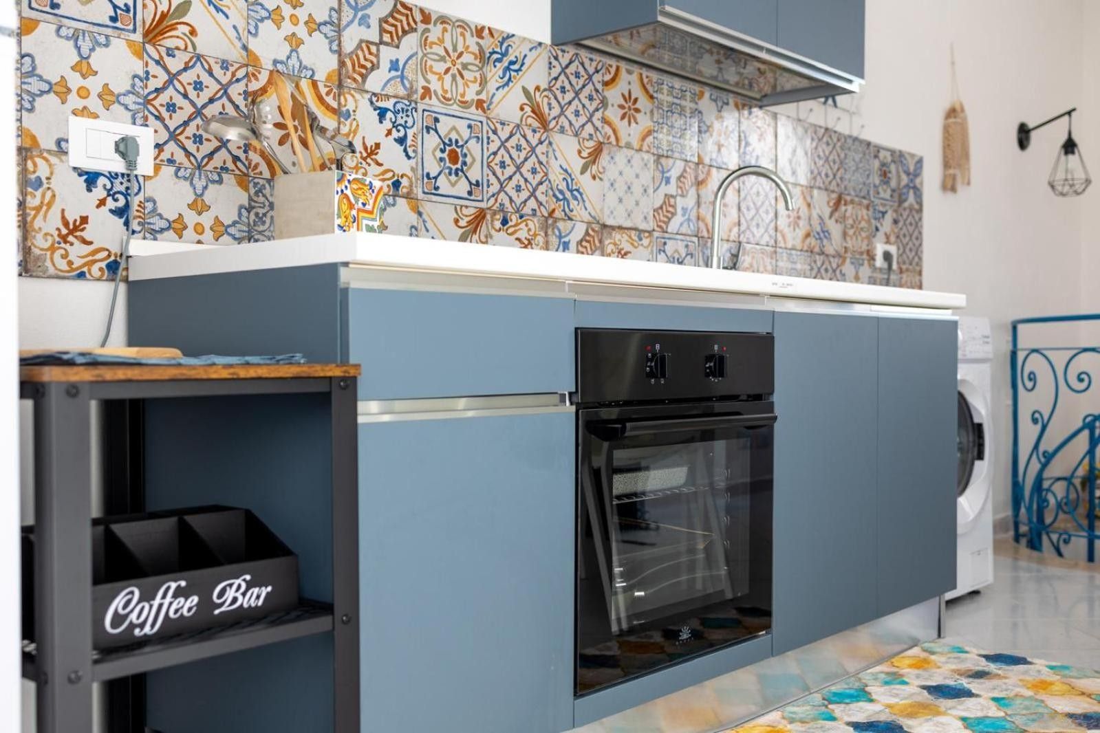 A compact kitchen with a built-in oven, a coffee bar, and a patterned backsplash.