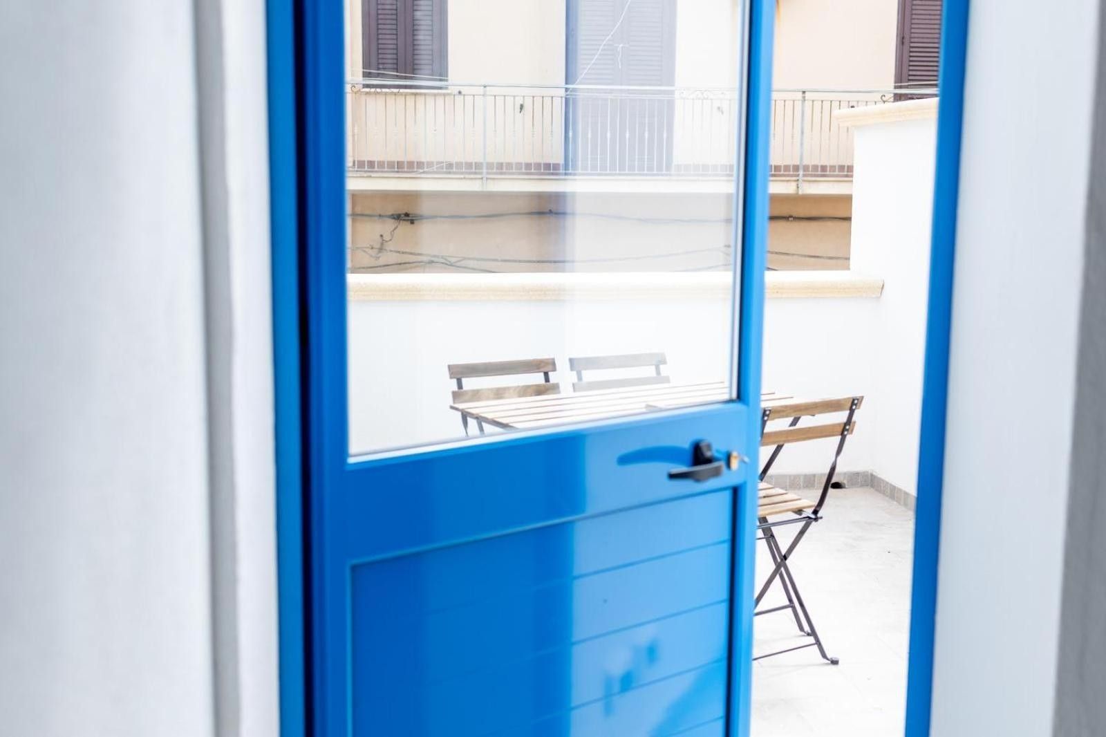 Eine blaue Tür, die zu einem Balkon mit Tisch und Stühlen führt.