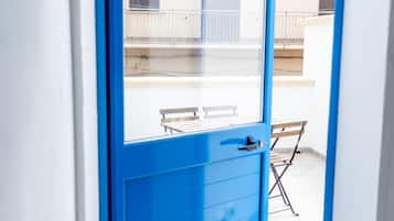 Eine blaue Tür, die zu einem Balkon mit Tisch und Stühlen führt.