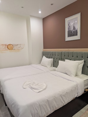Ein ordentlich bezogenes Bett mit weißen Leinen und einem Handtuch, ein gerahmtes Bild an der Wand und eine braune Akzentwand.