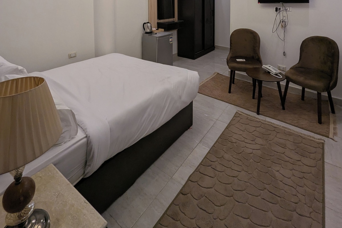 Ein modernes Hotelzimmer mit einem Bett, einem Schreibtisch, einem Fernseher und zwei Sesseln.