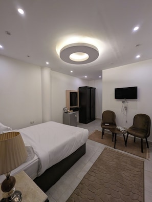 Ein modernes Hotelzimmer mit einem Bett, einem Schreibtisch, einem Fernseher und zwei Sesseln.