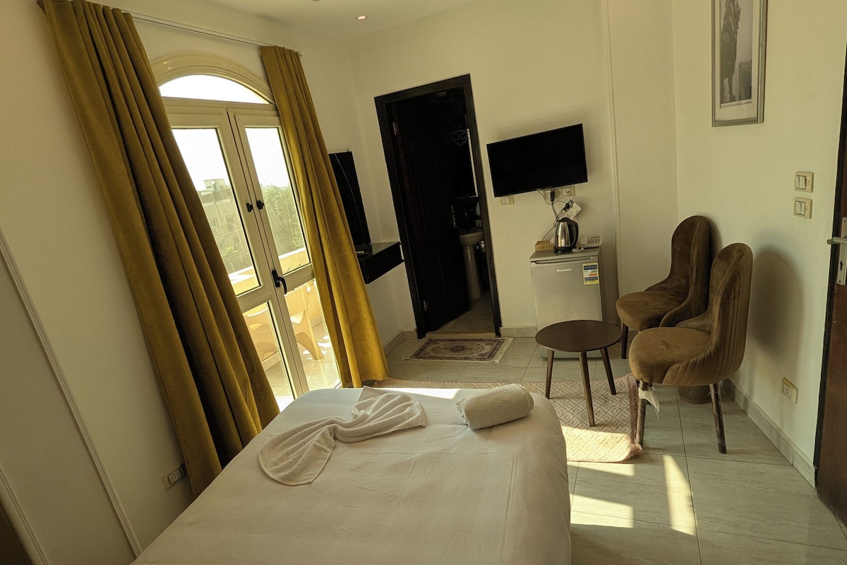 Ein Hotelzimmer mit einem Bett, einem Schreibtisch mit Computer, einem Stuhl und einem Fernseher.