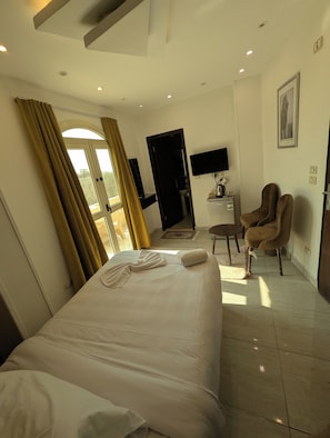 Ein Hotelzimmer mit einem Bett, einem Schreibtisch mit Computer, einem Stuhl und einem Fernseher.