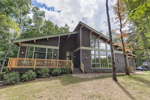 A modern two-story cabin with a wooden deck, large windows, and a stone pathway leading to the entrance. - New to the rental market. Perfect Getaway Chalet in Chinquapin (Glenville)