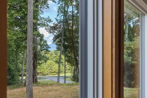 A view through a window of a forested area with a road. - New to the rental market. Perfect Getaway Chalet in Chinquapin (Glenville)