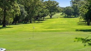 A golf course with a flag on the green, surrounded by trees. - Fairways at the Bay - Heated Pool and Green View (Nelson Bay)