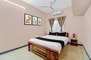 A bedroom with a bed, a ceiling fan, an air conditioning unit, and a window with curtains.