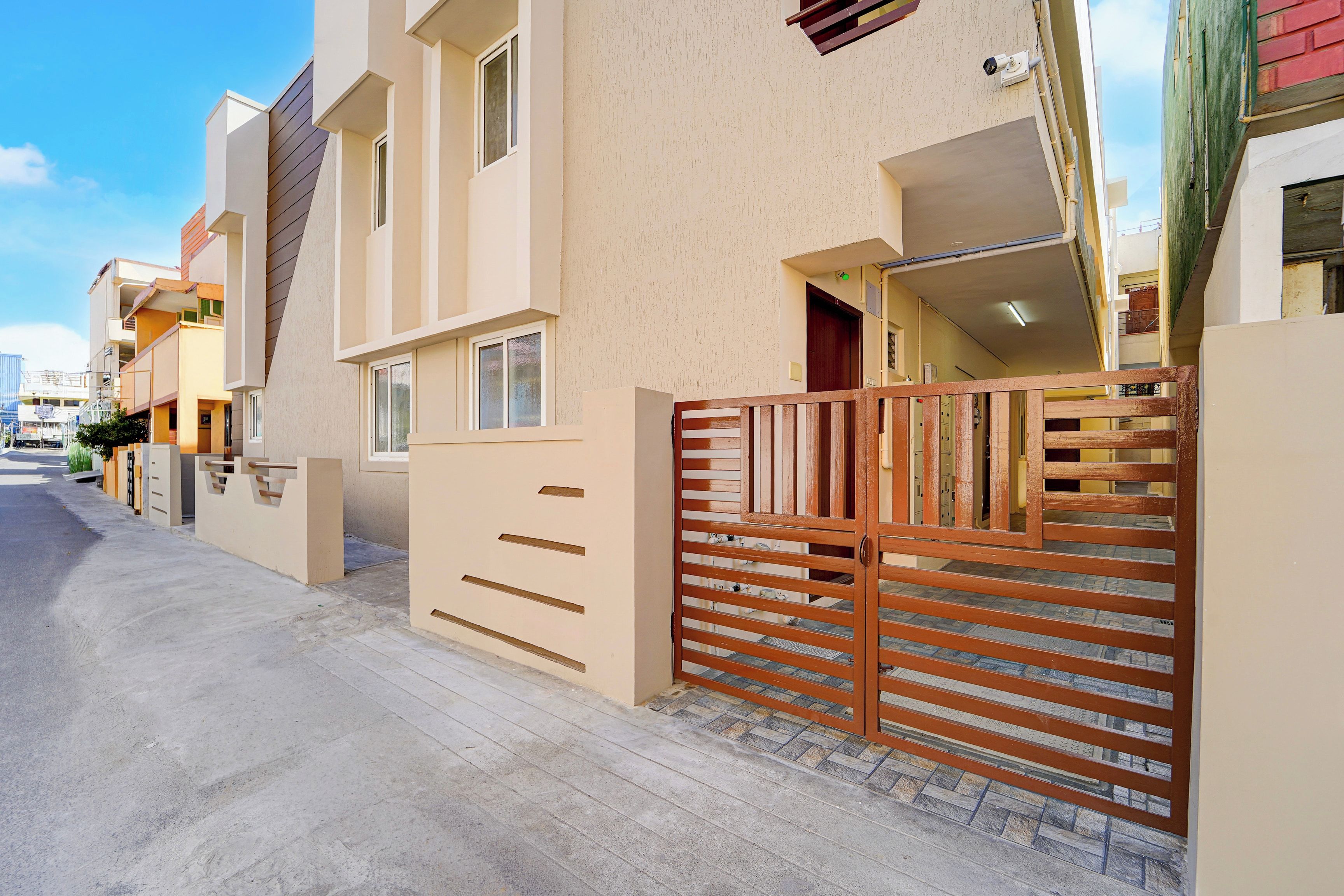Un edificio residencial con entrada protegida por un portón, una puerta visible y una ventana.
