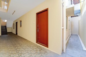 Un pasillo con una puerta de madera, una escalera y una ventana.