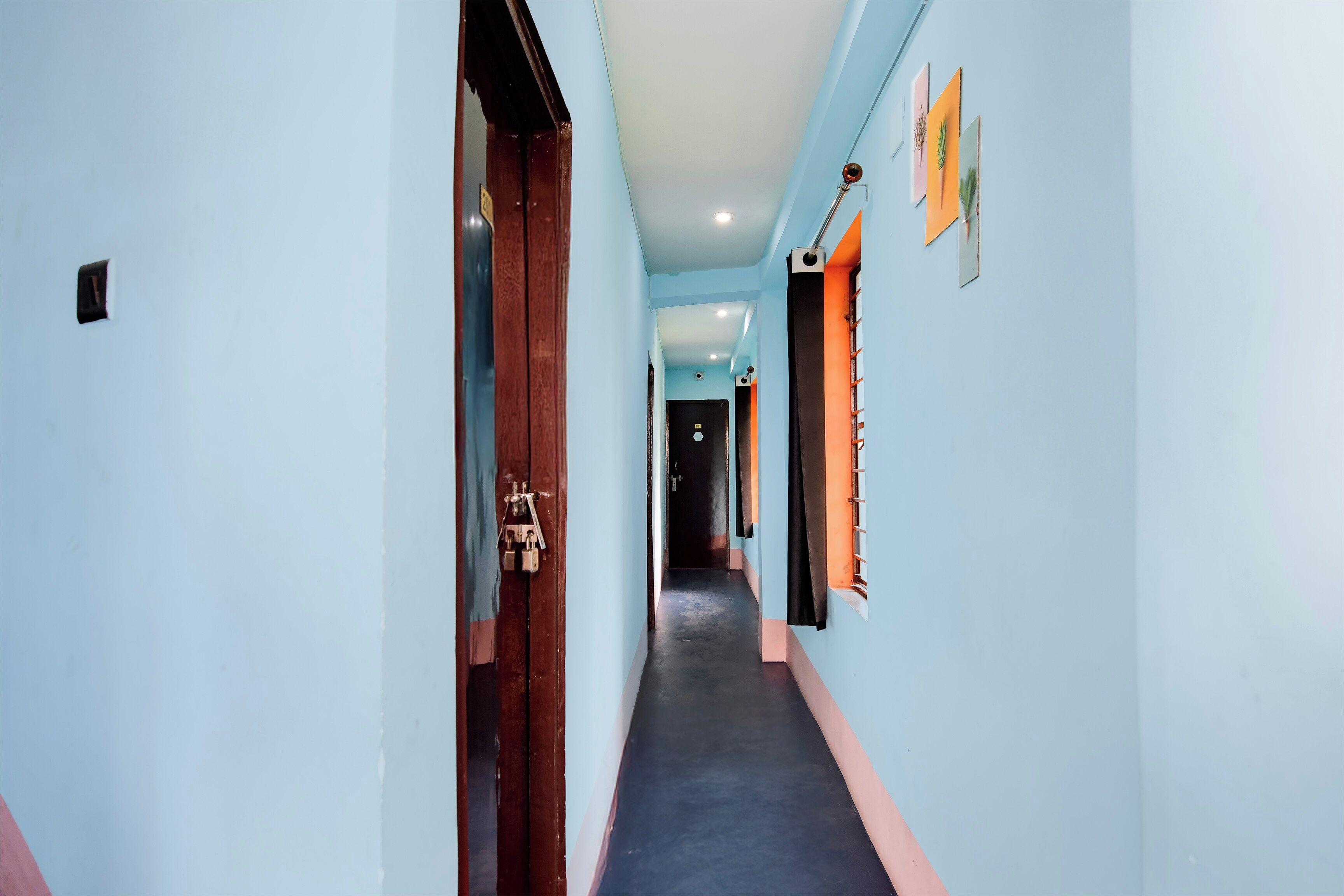 A corridor with a wooden door on the left and a window on the right.