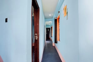 Un pasillo con una puerta de madera a la izquierda y una ventana a la derecha.