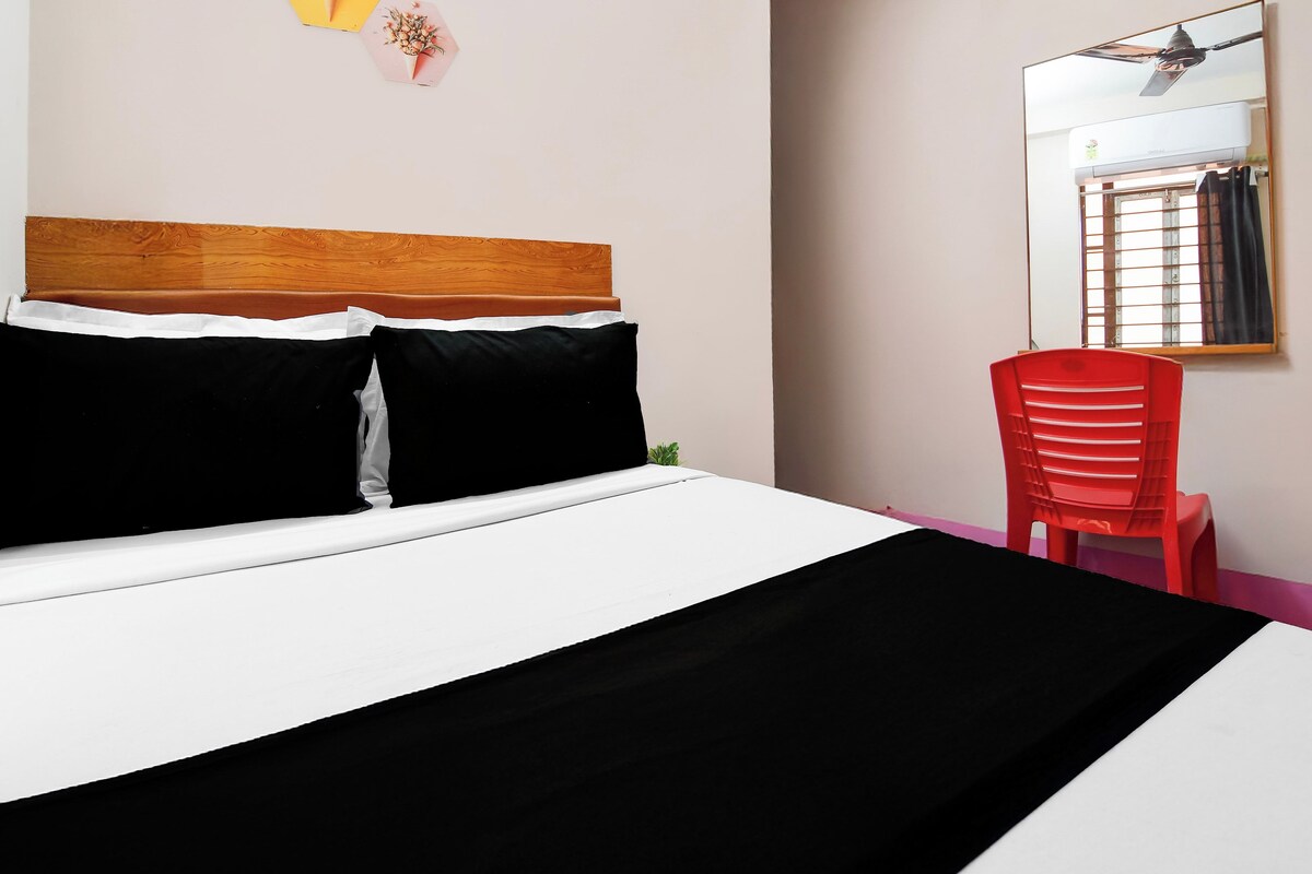 A bed with a wooden headboard, a red chair, and a window with a view of the outside.