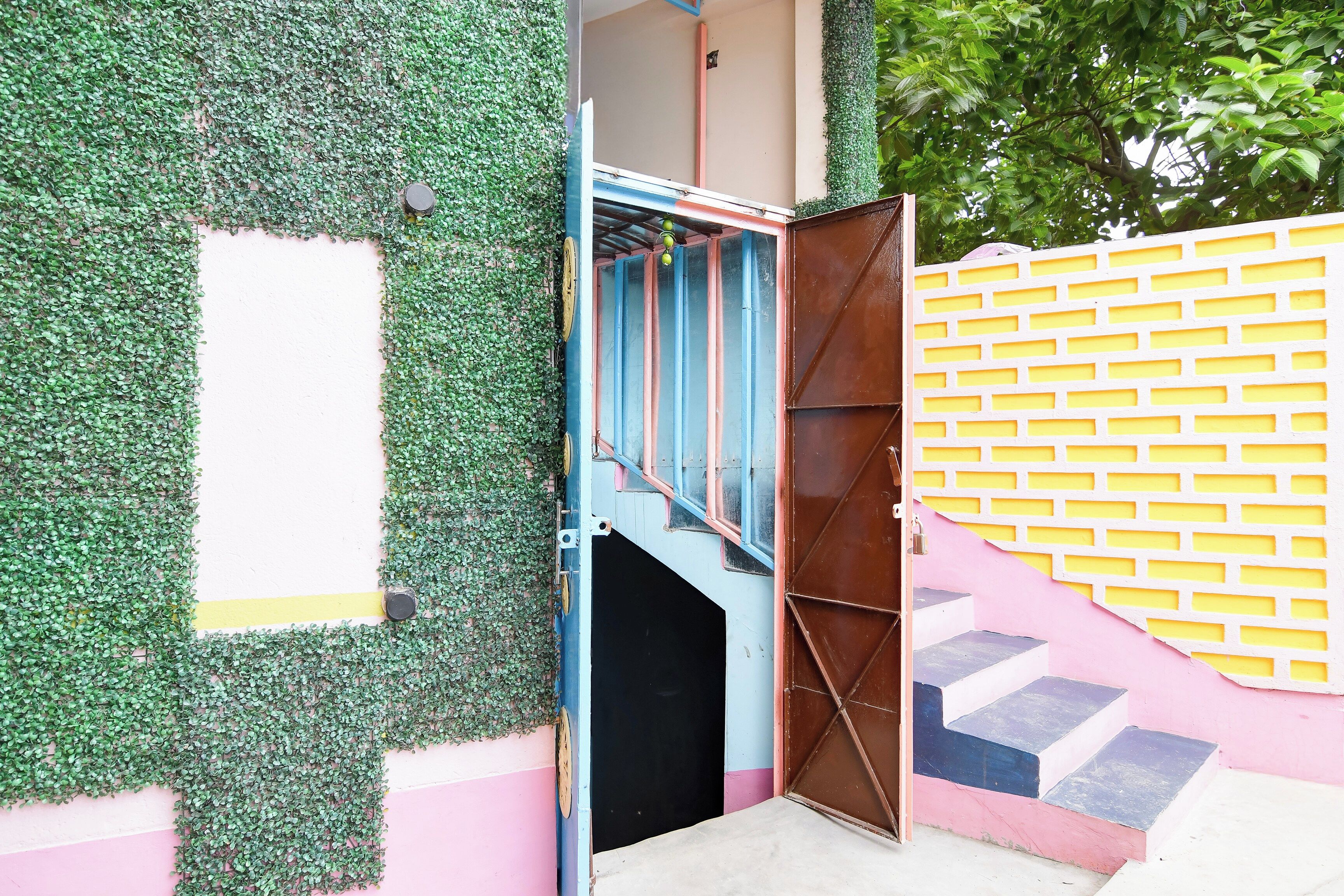 Una entrada de edificio con un muro verde, una puerta azul y una valla amarilla.