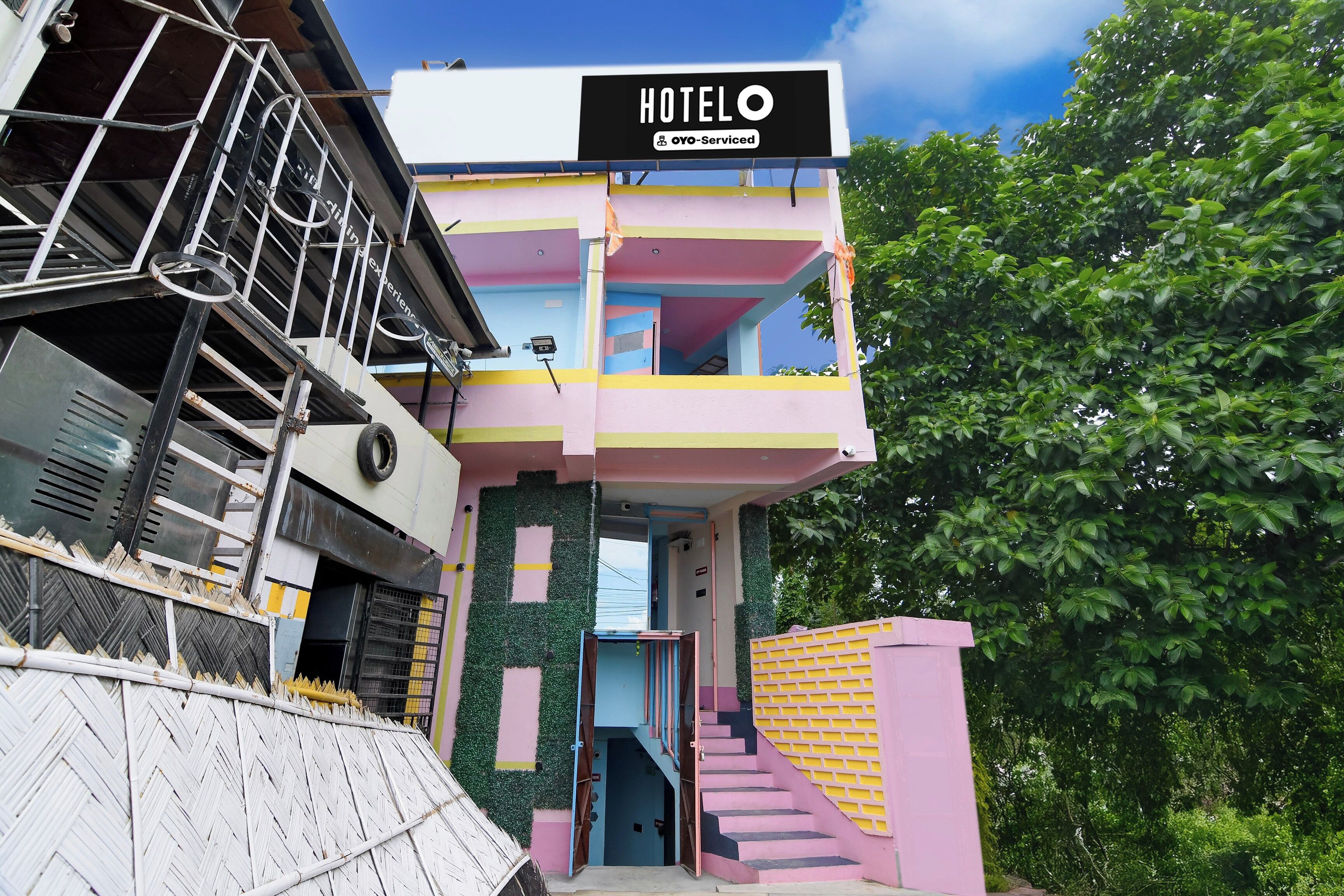 Un hotel de varios pisos con fachada colorida, una escalera visible y un letrero que indica que es administrado por una empresa específica.