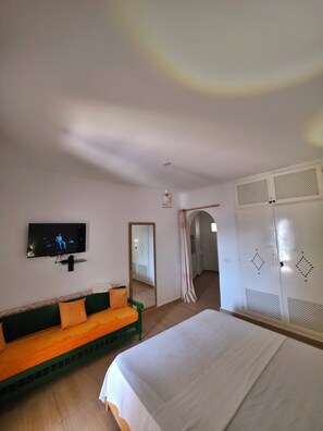 Ett hotellrum med en säng, en soffa, en tv, en spegel och en garderob.