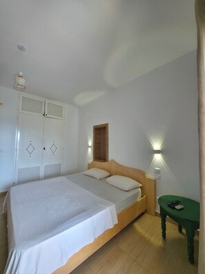 A bedroom with a bed, a wardrobe, a bedside table, and a wall-mounted light fixture. - Apartment marina kantaoui sousse (Hammam Sousse)
