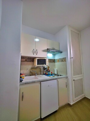 A compact kitchen with white cabinets, a microwave, a sink, and a small refrigerator. - Apartment marina kantaoui sousse (Hammam Sousse)