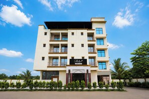 Un hotel de varios pisos con fachada plana y balcones en cada nivel, con un letrero que indica que es administrado por OYO.