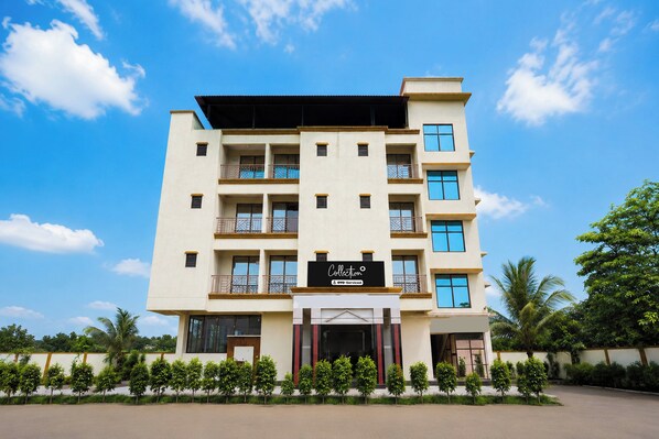 Un hotel de varios pisos con fachada plana y balcones en cada nivel, con un letrero que indica que es administrado por OYO.