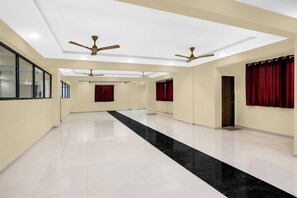 A spacious hallway with ceiling fans, red curtains, and a black strip on the floor.