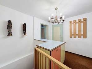Ein Zimmer mit weißer Wand, einer Holztür, einem Chandelier und einem kleinen Tisch.