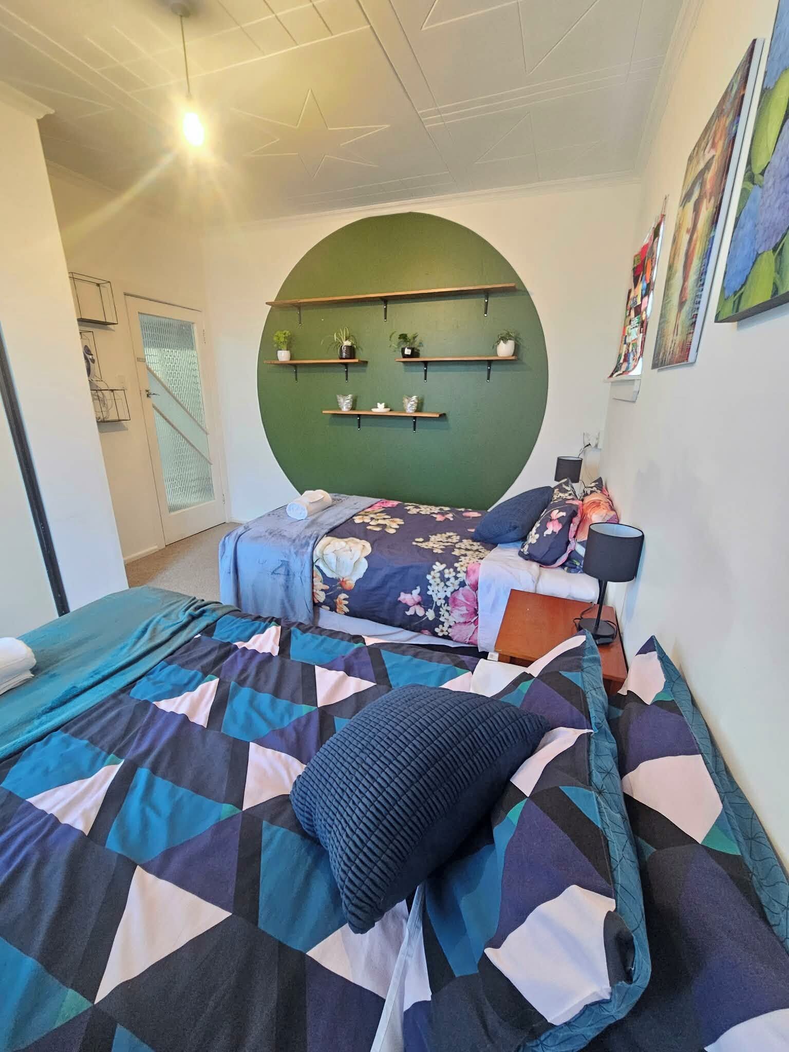 Ein Schlafzimmer mit einem Bett, einer grünen Wand und einer Deckenleuchte.