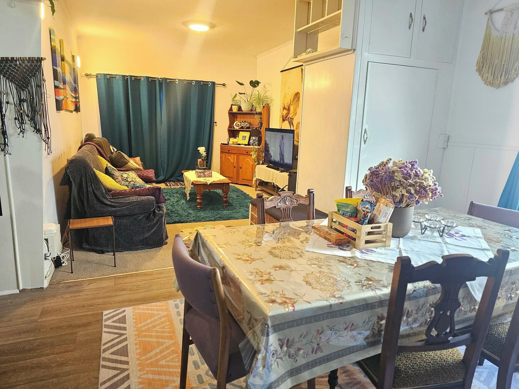 A cozy living room with a sofa, a television, and a dining table with chairs.