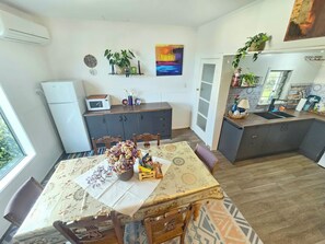 A compact kitchen with a dining table, chairs, a refrigerator, and a microwave.
