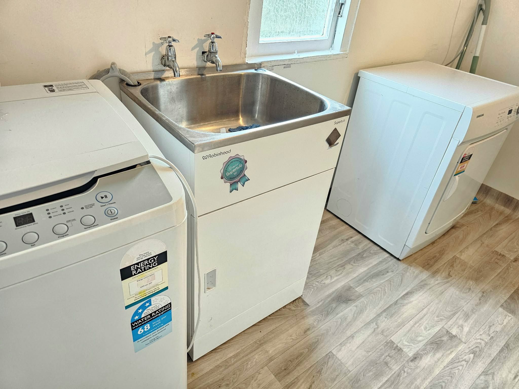 A compact laundry room with a washing machine, a dryer, and a small sink.