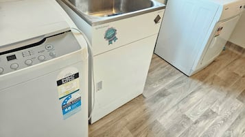 A compact laundry room with a washing machine, a dryer, and a small sink.
