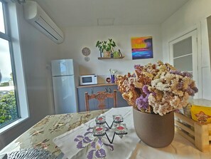 A kitchen with a refrigerator, microwave, and a dining table with a floral tablecloth.